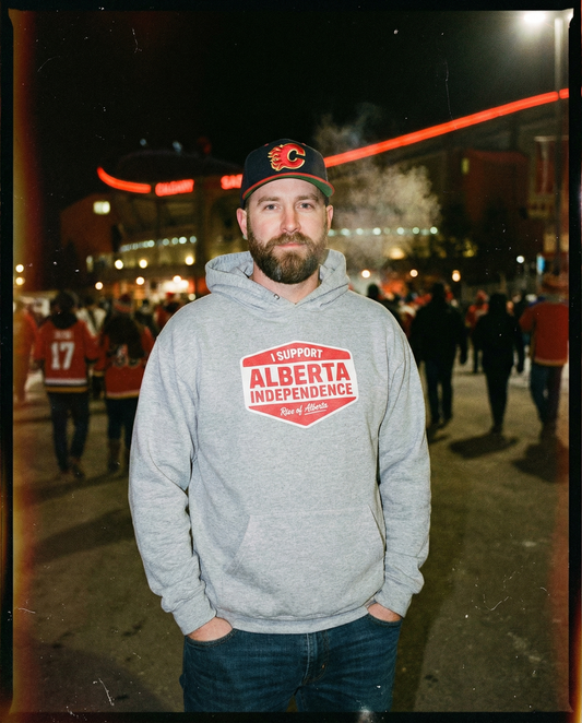 Man wearing a hoodie with 'I Support Alberta Independence' text at a nighttime event.