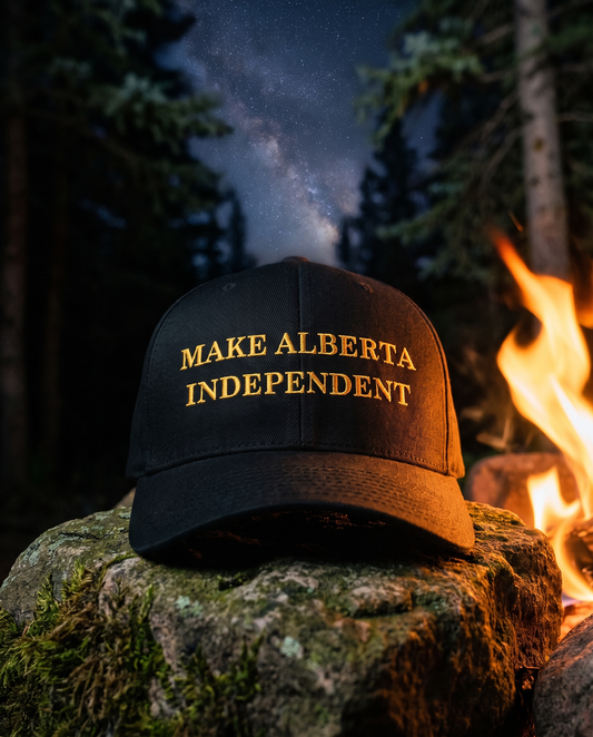 A black baseball cap with 'MAKE ALBERTA INDEPENDENT' embroidered in gold lettering, resting on a mossy rock next to a campfire in a forest at night.