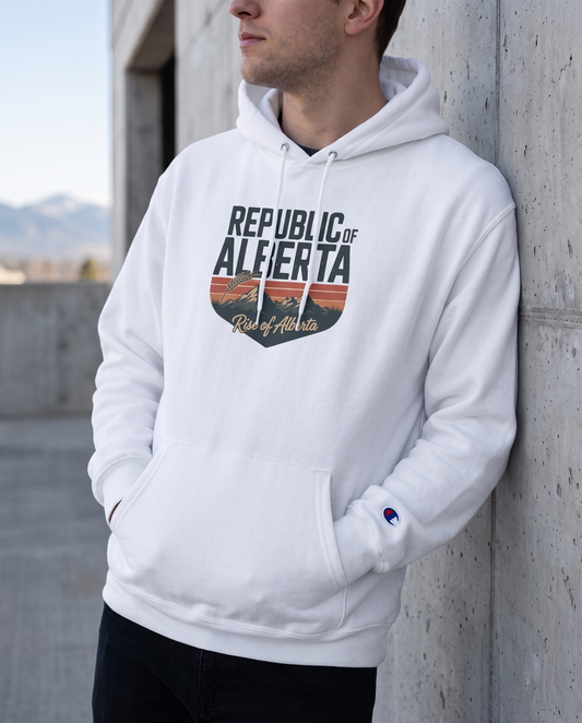 Man wearing white Republic of Alberta Champion hoodie against concrete wall