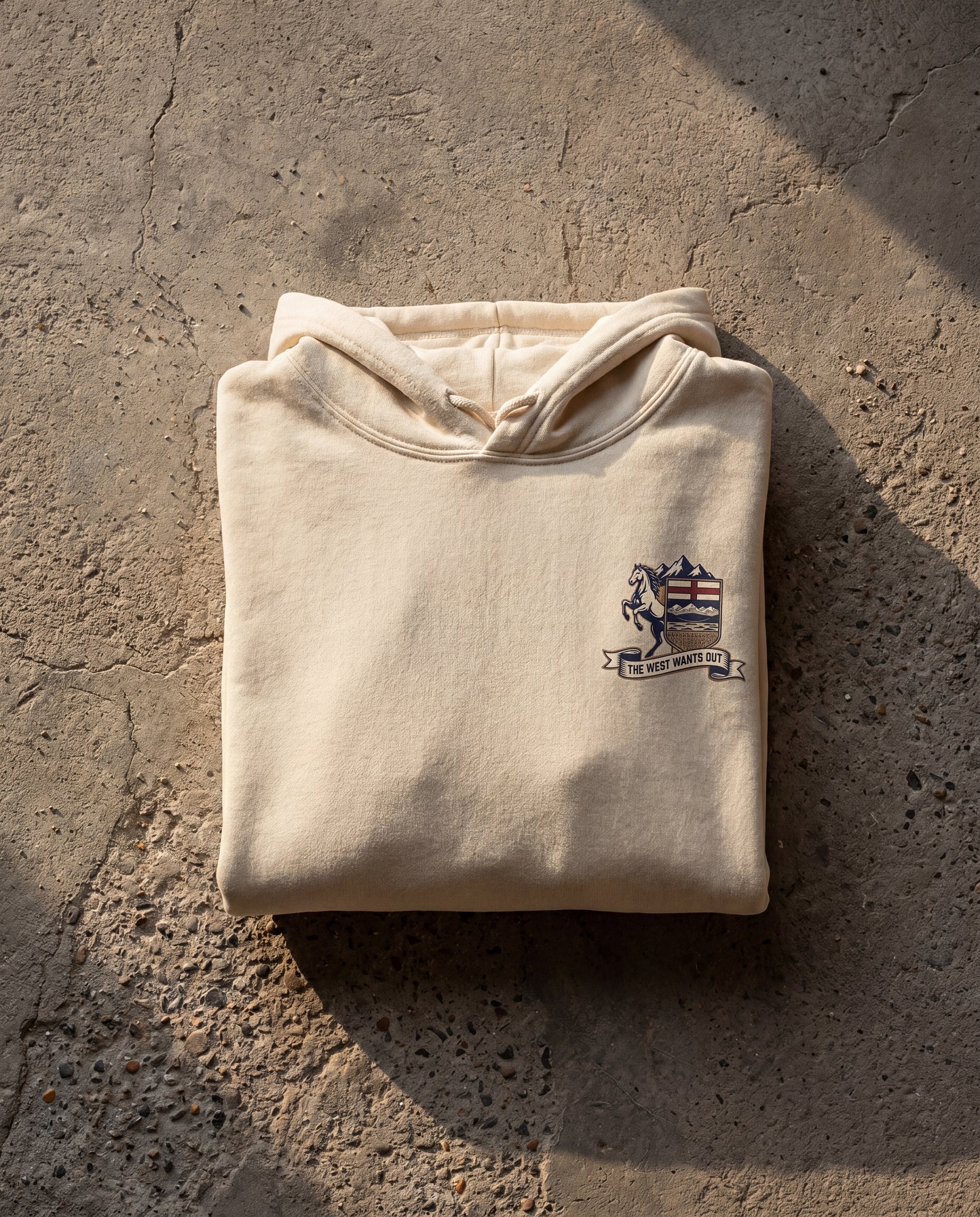 Folded beige hoodie with a logo on a textured stone surface