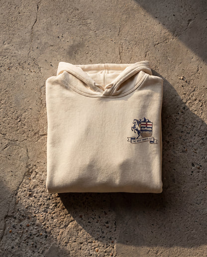Folded beige hoodie with a logo on a textured stone surface