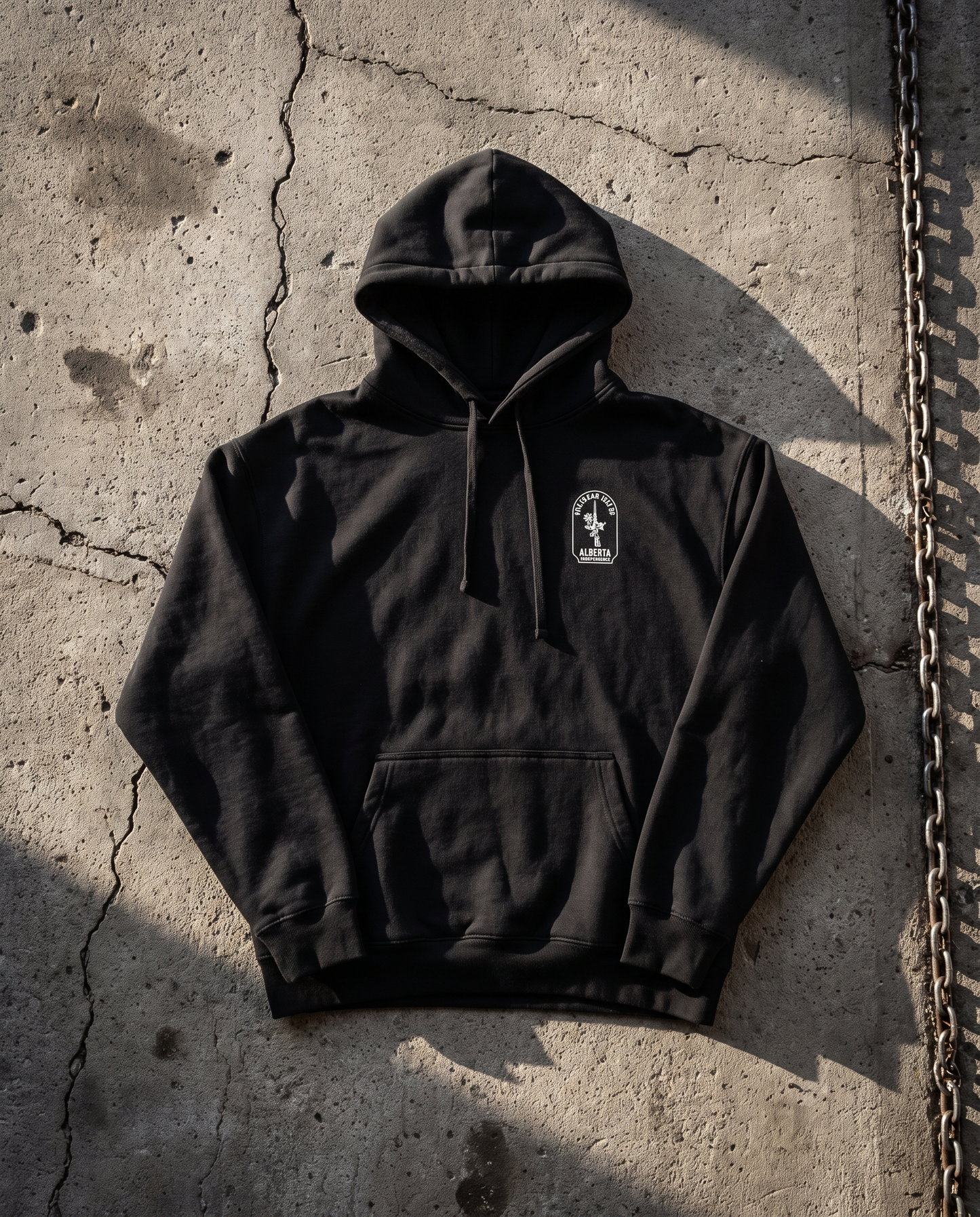 Firearm Heritage black hoodie front with chest badge flat lay on concrete