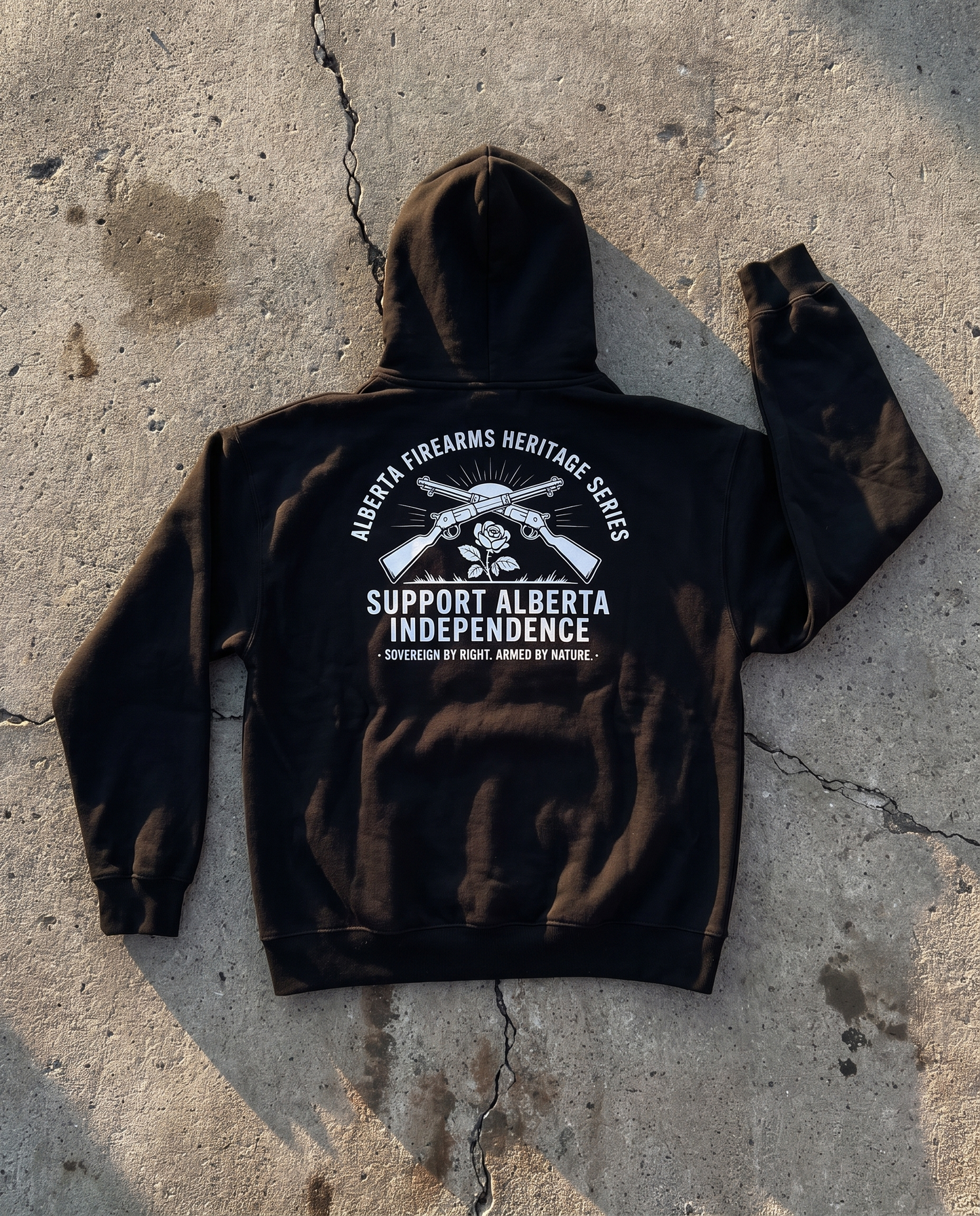 Firearm Heritage black hoodie back print flat lay on cracked concrete