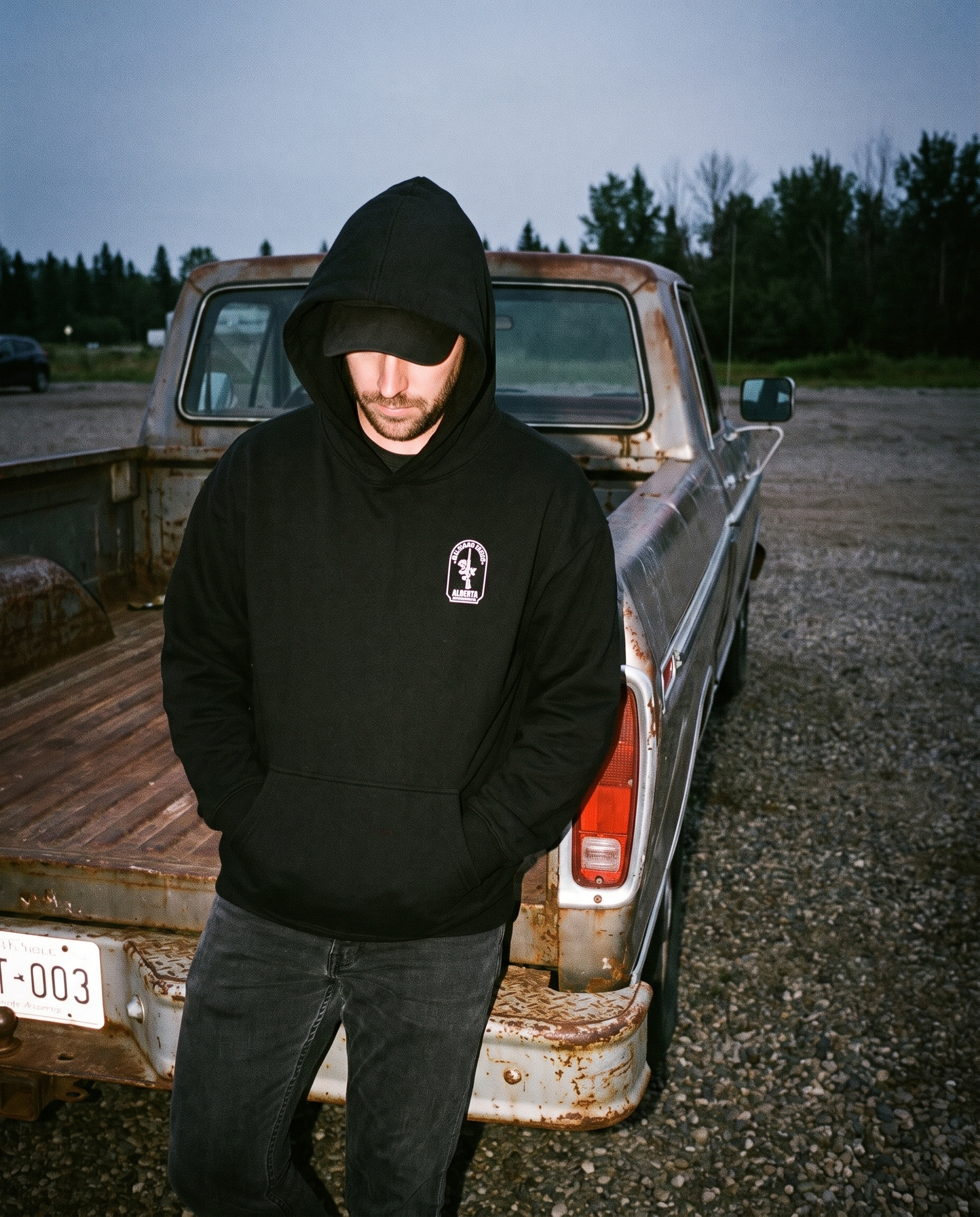 Man wearing Firearm Heritage hoodie hood up by pickup truck dusk flash photo