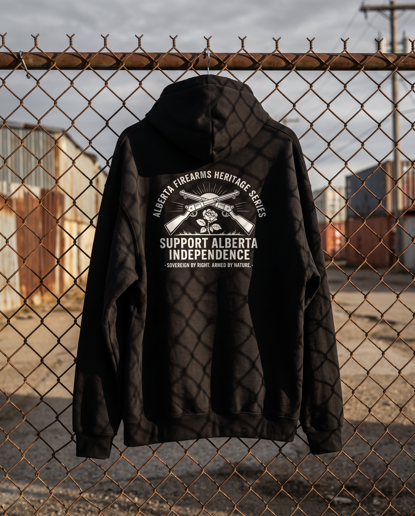 Firearm Heritage hoodie hanging on chain link fence showing back print