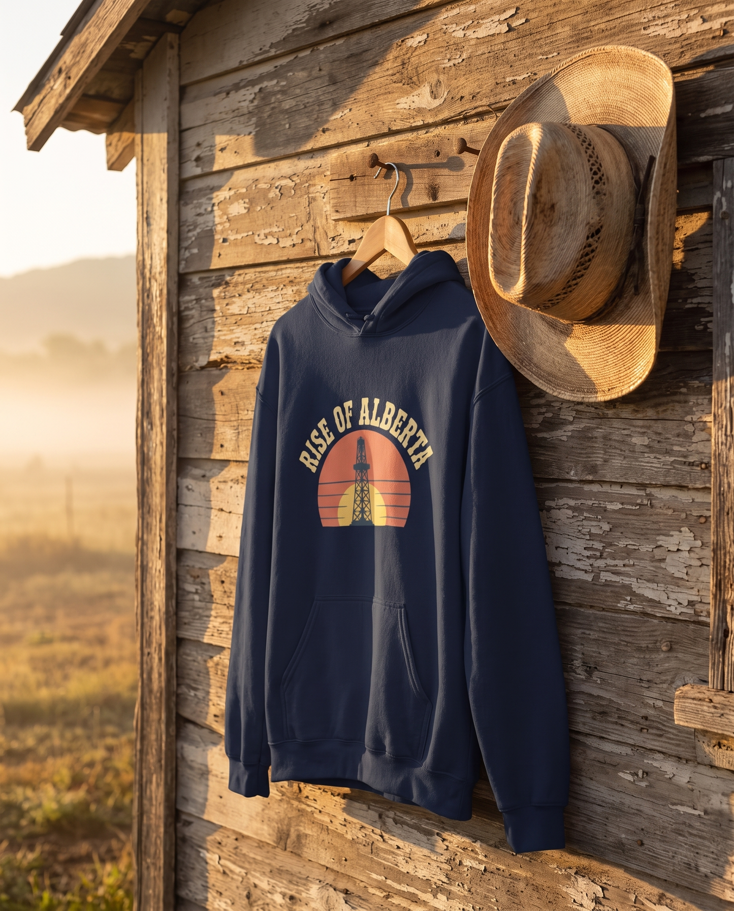 Rise of Alberta Sunrise Hoodie navy on rustic hook at dawn