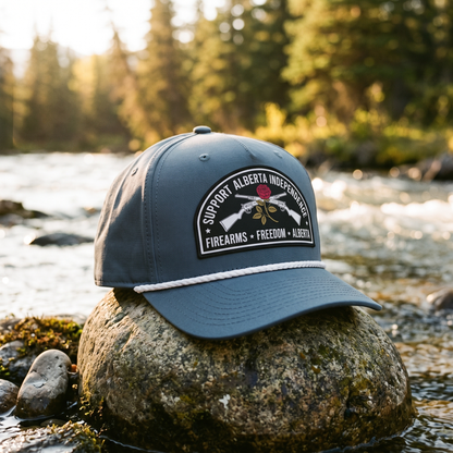 Alberta Firearms Freedom Rope Hat in slate blue on a river stone at a mountain creek