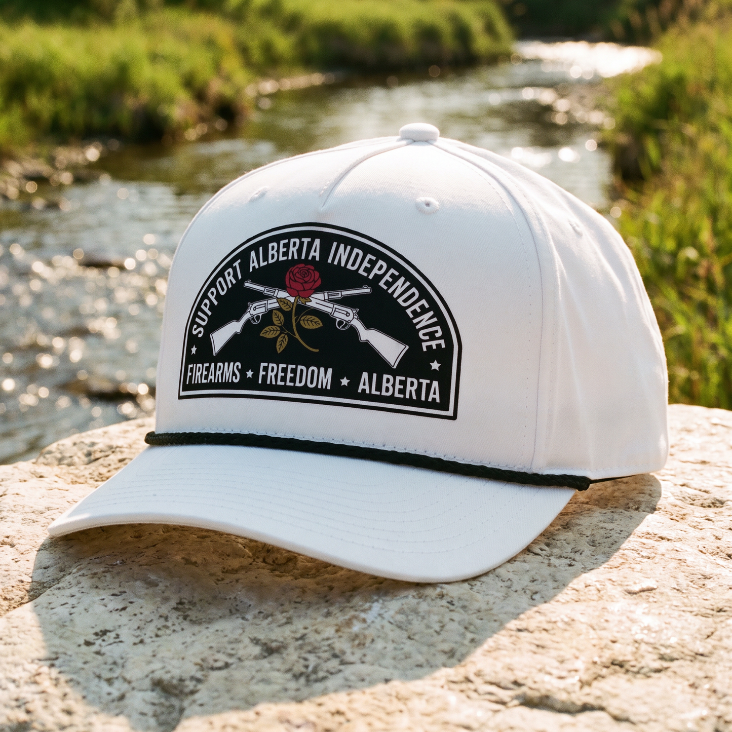 Alberta Firearms Freedom Rope Hat in white on a rock beside a creek