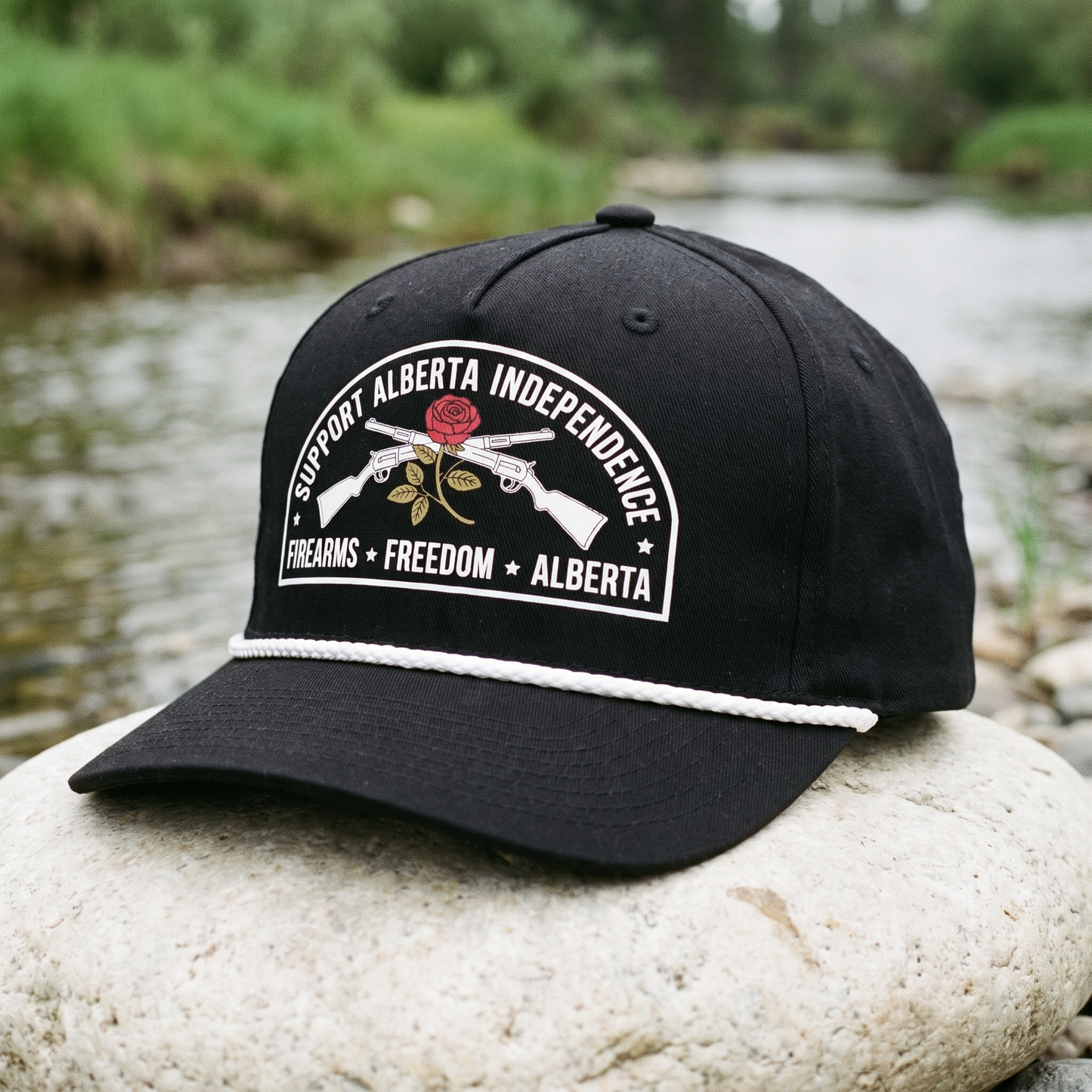 Alberta Firearms Freedom Rope Hat in black on a river stone beside a creek
