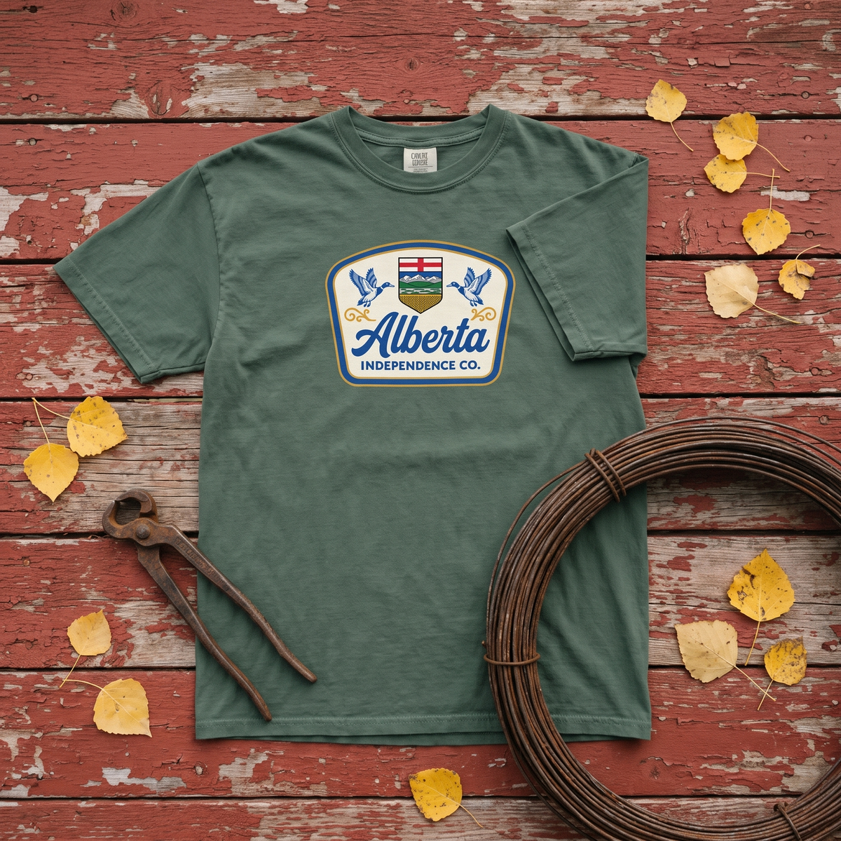 Alberta Independence Co. Heritage Tee in Blue Spruce, flat lay on barn red boards