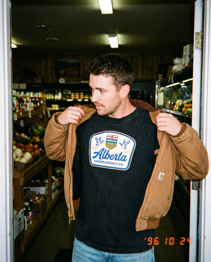 Heritage Tee in Black worn in a farm shop doorway