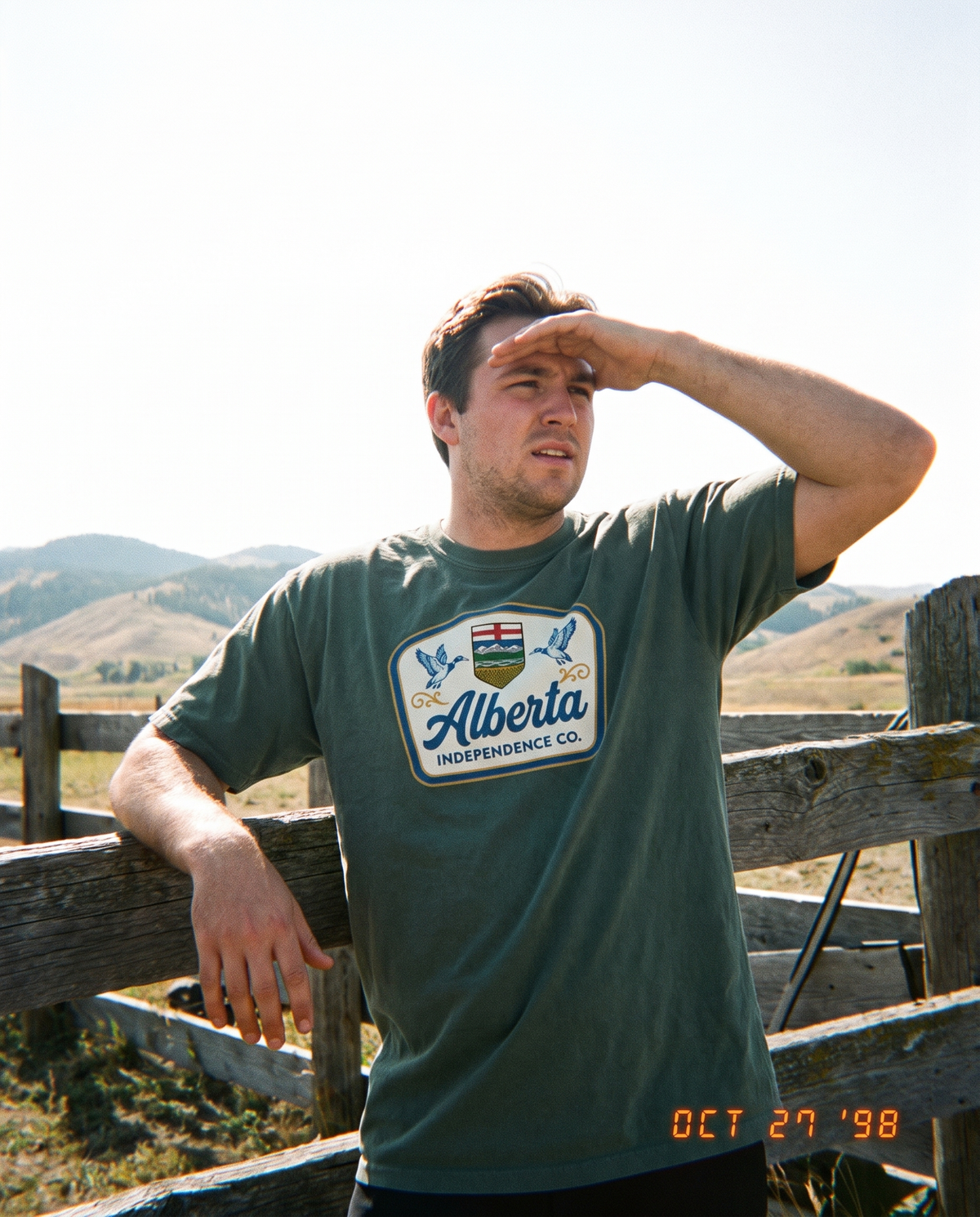 Heritage Tee in Blue Spruce worn at a fence line in the foothills
