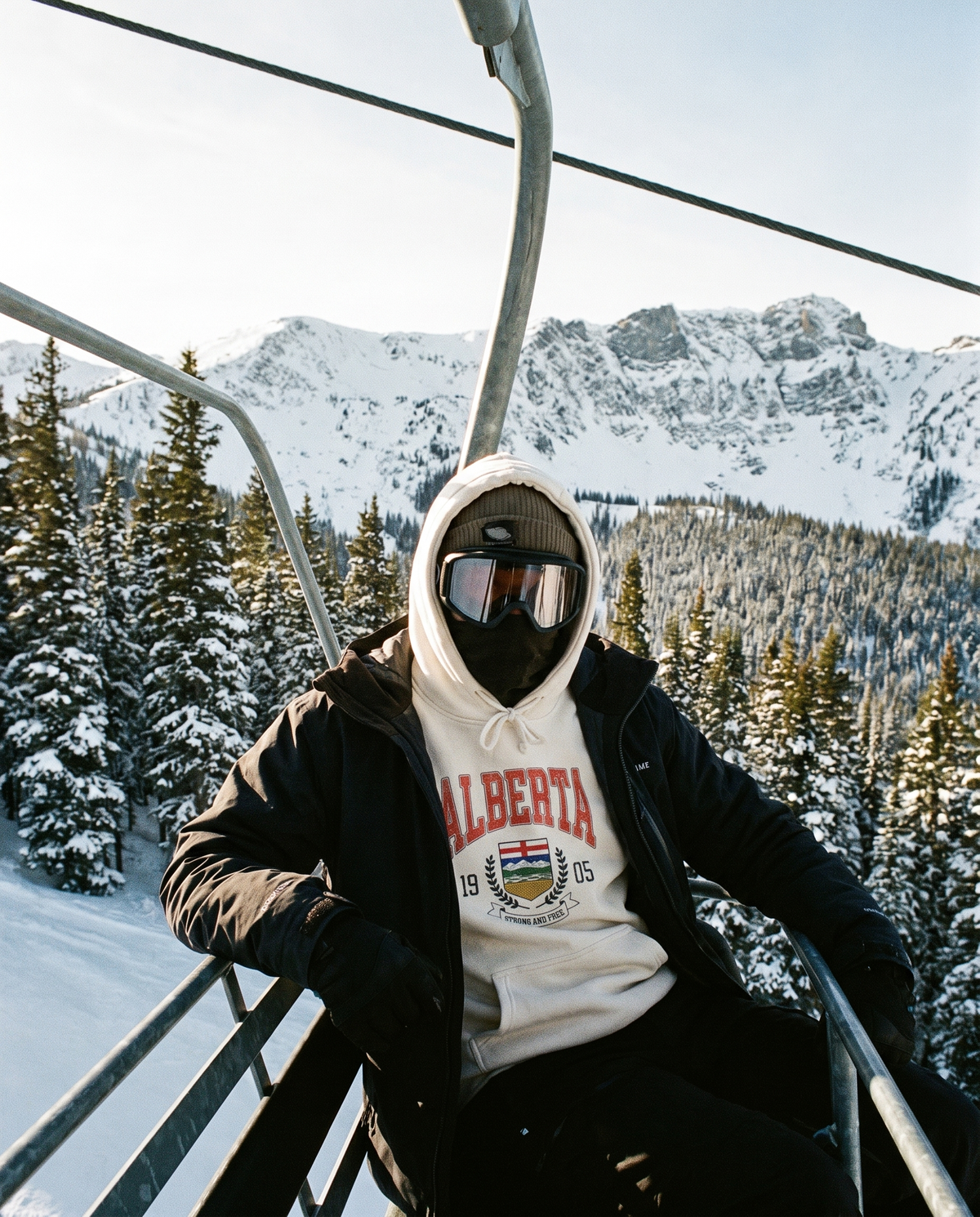 Alberta Coat of Arms Hoodie worn on a chairlift at an Alberta ski hill