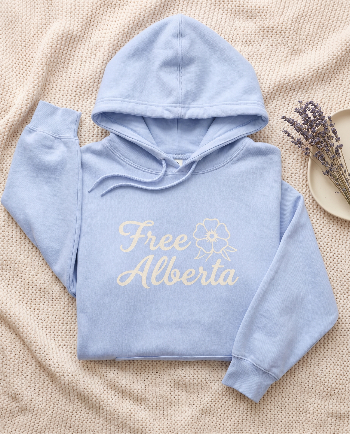 Free Alberta lightweight hoodie in Hydrangea blue flat lay on a knit blanket